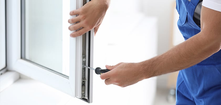 Homme manipulant une fenêtre avec une tournevis