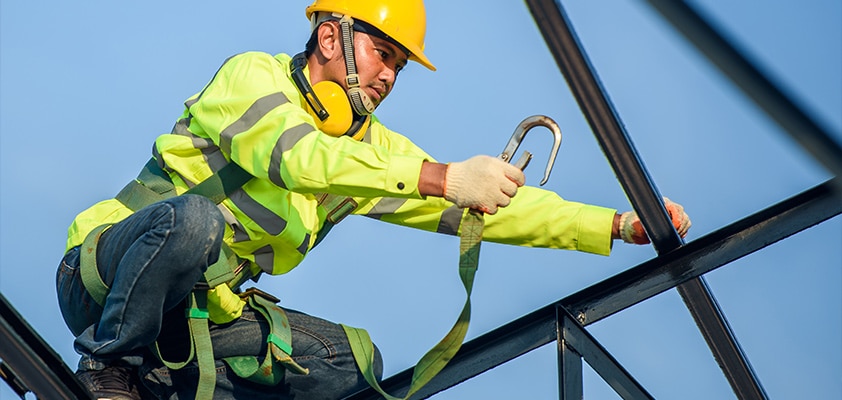 Homme en tenu de chantier avec un harnais dans un chantier en plein air